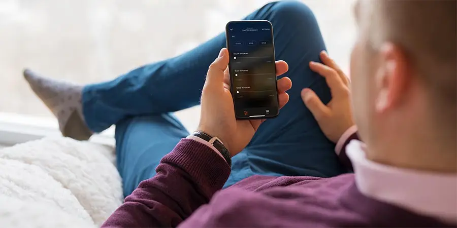 Person using smartphone app to control smart window shades